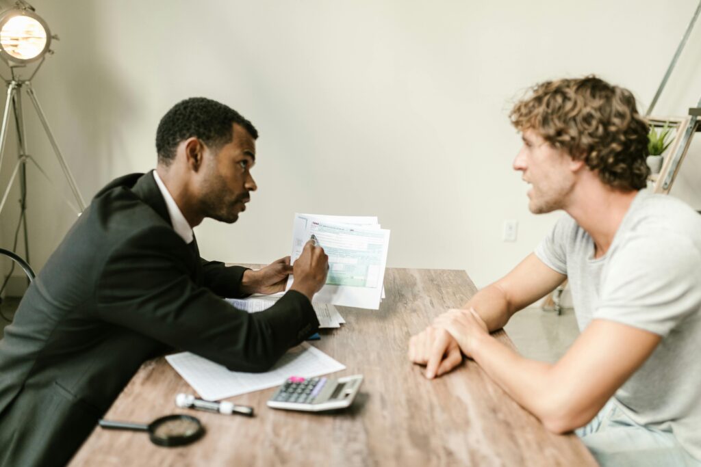 pexels-photo-7821671-7821671 A financial advisor discusses paperwork with a client at a desk in a modern office.
